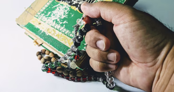 "يد تمسك بمسبحة قرآنية أثناء التأمل والتدبر في آيات القرآن الكريم"
