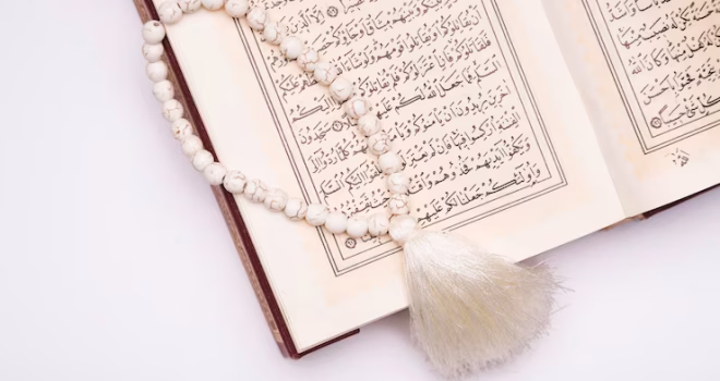 مصحف مفتوح على طاولة مع ضوء هادئ، رمزًا لتدبر القرآن واختيار السور المحببة إلى الله.